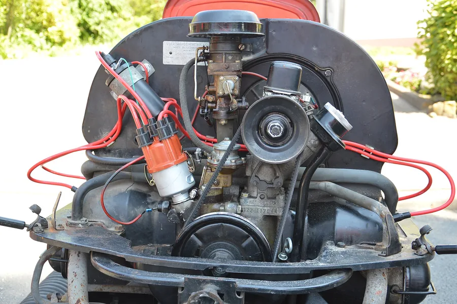 An air-cooled flat-four engine on a hoist, lowered into the rear bay of a bus.